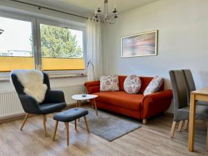 a living room with a red couch and two chairs at Haus Vogelsand, App 324 in Cuxhaven