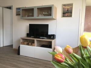 a living room with a television on a white entertainment center at Haus Vogelsand, App 324 in Cuxhaven