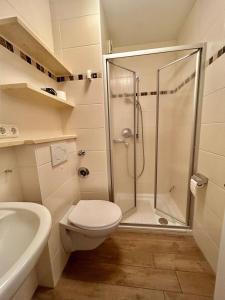 a white bathroom with a shower and a toilet at Haus Vogelsand, App 324 in Cuxhaven