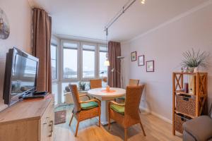 a living room with a table and chairs and a television at Haus Knechtsand, Whg 433 in Cuxhaven