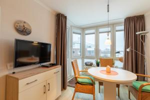 a living room with a television and a table with chairs at Haus Knechtsand, Whg 433 in Cuxhaven