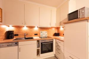 a kitchen with white cabinets and a sink and a microwave at Haus Knechtsand, Whg 433 in Cuxhaven +23 photos