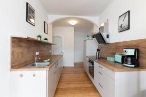 a kitchen with white cabinets and a wooden counter top at Wohnung Deichbude in Cuxhaven