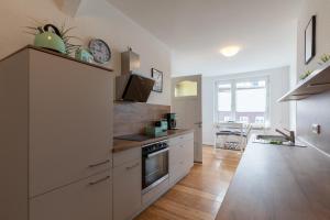 a kitchen with white cabinets and a clock on the wall at Wohnung Deichbude in Cuxhaven