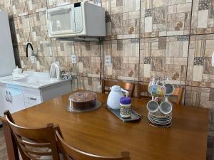 a kitchen with a table with a cake and a microwave at Canto do viajante in São Gabriel +18 photos