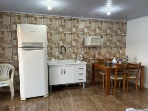 a kitchen with a white refrigerator and a table at Canto do viajante in São Gabriel