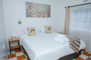 a bedroom with a white bed with towels on it at Lion Hill Place in Nakuru