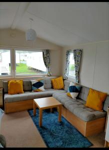 een woonkamer met een bank en een tafel bij Sycamores Caravan in Helston