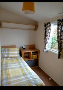 een kleine slaapkamer met een bed en een raam bij Sycamores Caravan in Helston