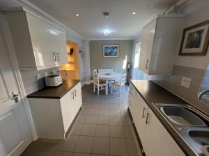 a kitchen with white cabinets and a sink and a table at Siskin House in Wickham Market