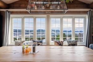 a dining room with a large wooden table and windows at TH616- Large ski-in out cabin in Trysilfjell for 14 guests in Trysil