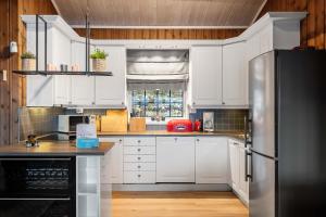 a kitchen with white cabinets and a stainless steel refrigerator at TH616- Large ski-in out cabin in Trysilfjell for 14 guests in Trysil