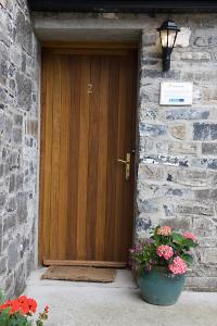 a wooden door in a stone building with a pot of flowers at The Henhouse, Duffys of Ballybin, 4-star in The Crockan
