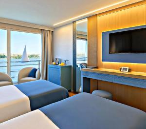 a hotel room with two beds and a flat screen tv at Five-Star Deluxe River Kruz from Aswan to Luxor 3 Nights in Aswān