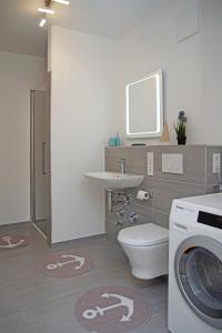 a bathroom with a toilet and a sink and a washing machine at Haus Yachthafen, Whg 4 in Cuxhaven +2 photos