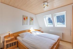 a bedroom with a bed with white sheets and two windows at Seegras in Cuxhaven