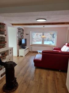 a living room with a red couch and a tv at Ferienwohnung Braun in Longkamp