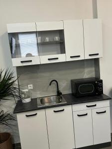 a kitchen with white cabinets and a sink and a microwave at Aura Apartment 2 Herne in Herne