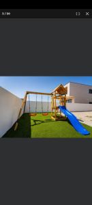 a playground with a blue slide on a grass field at Petra in Biograd na Moru