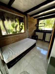 a bed in a room with two large windows at Sítio Araripe Eco House in Santa Cruz Cabrália