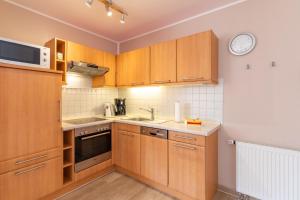 a kitchen with wooden cabinets and a clock on the wall at Haus Weser, Whg 2 in Döse
