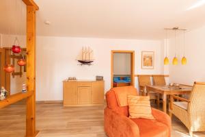 a living room with an orange chair and a table at Haus Weser, Whg 2 in Döse