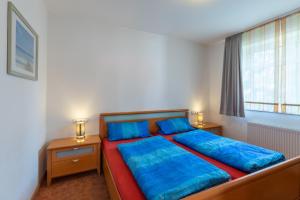 a bedroom with a bed with blue sheets and a window at Haus Weser, Whg 2 in Döse +5 photos