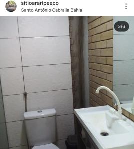 a bathroom with a white toilet and a sink at Sítio Araripe Eco House in Santa Cruz Cabrália
