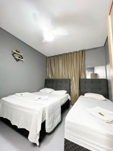 two beds in a room with white sheets at Hostel Anprado #4 Kit café incluso, Próx-Aeroporto de Guarulhos in Guarulhos