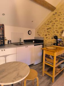 a kitchen with a table and a sink and a table at Le petit grenier de la Quoiqueterie in Vieille-Église-en-Yvelines
