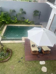 an umbrella and chairs next to a swimming pool at Villa Elina 09 in Badung