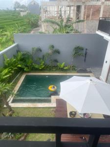 a pool with a white umbrella and a ball in it at Villa Elina 09 in Badung +2 photos