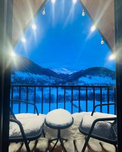 een balkon met uitzicht op de met sneeuw bedekte bergen bij Mountain Shadow Cottage in Racha in Ghebi
