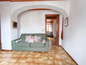 a living room with a green couch and an archway at Da Anny - Valdilana in Coggiola