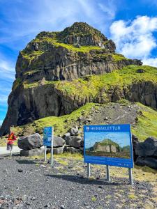 a mountain with two signs in front of it at Þórsheimili - Rooms in Vestmannaeyjar