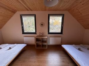 twee bedden in een kamer met twee ramen bij Domki Gorąca Bania in Gowidlino