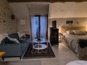 a living room with a couch and a bed at Le petit grenier de la Quoiqueterie in Vieille-Église-en-Yvelines