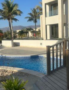 a swimming pool next to a building with palm trees at Cosy 1BR with a PUBLIC POOL and WIFI in Ma‘mūrah