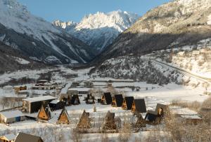 a village covered in snow with mountains in the background at Winterfell Mestia - Premium Chalet Complex & SPA in Mestia