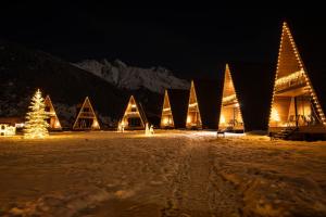 a building with christmas lights in the snow at night at WinterFell Mestia in Mestia