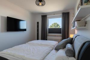 a bedroom with a bed and a tv and a window at Haus Medemsand, Whg 221 in Duhnen