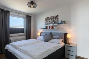 a bedroom with a large bed and a window at Haus Medemsand, Whg 221 in Duhnen +18 photos