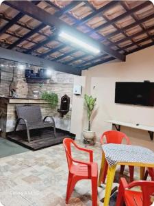 a living room with a table and chairs and a television at Varanda Praiana in Rio das Ostras