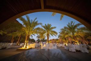 eine Gruppe von Tischen und Stühlen mit Palmen in der Unterkunft Sahary Al Ula Resort in Al-'Ula