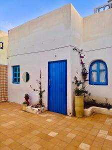 a blue door on a white building with potted plants at Global Surf GuestHouse in Sidi Kaouki
