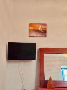a flat screen tv hanging on a wall next to a mirror at Global Surf GuestHouse in Sidi Kaouki