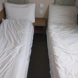 two beds with white sheets and a wooden table in a room at The vintage in Winthorpe