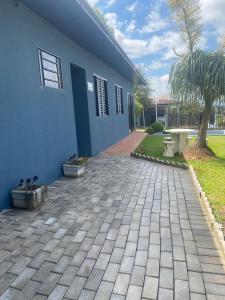 a blue house with a brick driveway at Suíte privativa quarto in Xaxim