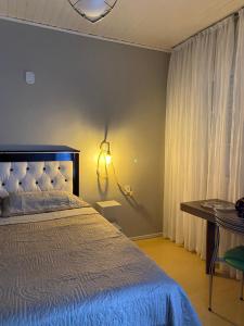 a bedroom with a bed and a table and a window at Suíte privativa quarto in Xaxim