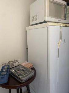 a microwave on top of a refrigerator next to a table at Suíte privativa quarto in Xaxim